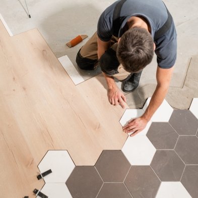 flooring installer combining ceramic and wood flooring in a modern pattern at Eagle Flooring in Swansea, IL